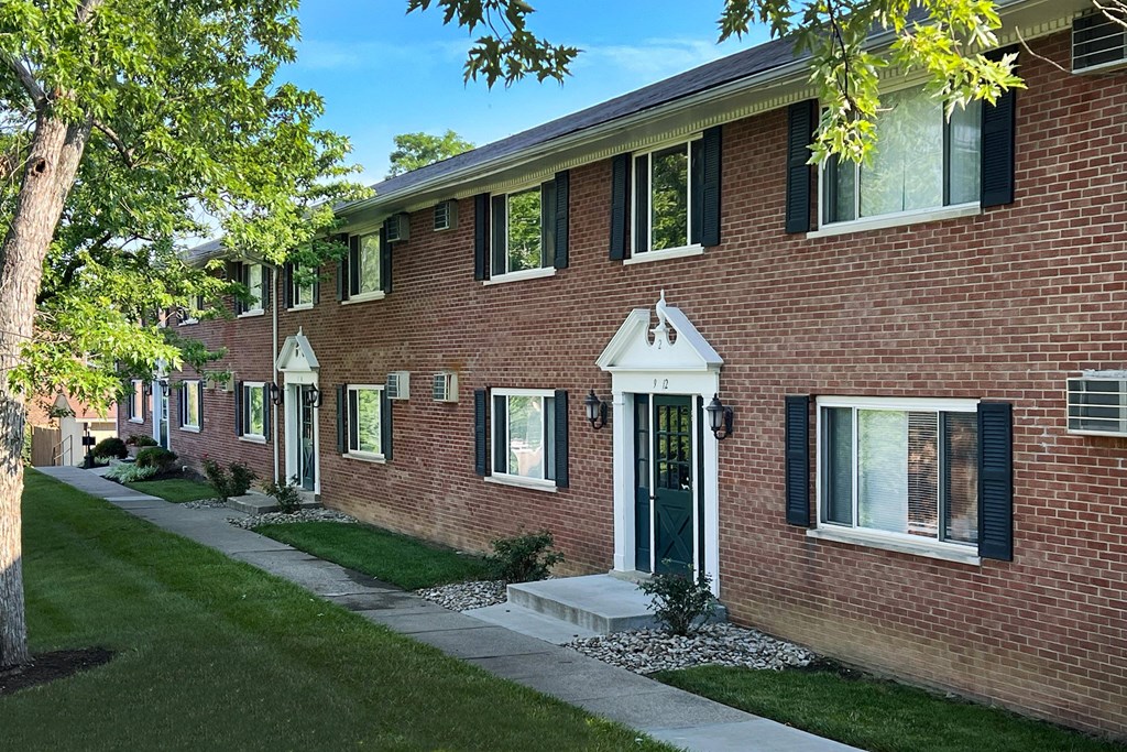 a red brick building with a green lawn and a sidewalk at Sharondale Woods Apartments, Cincinnati, OH