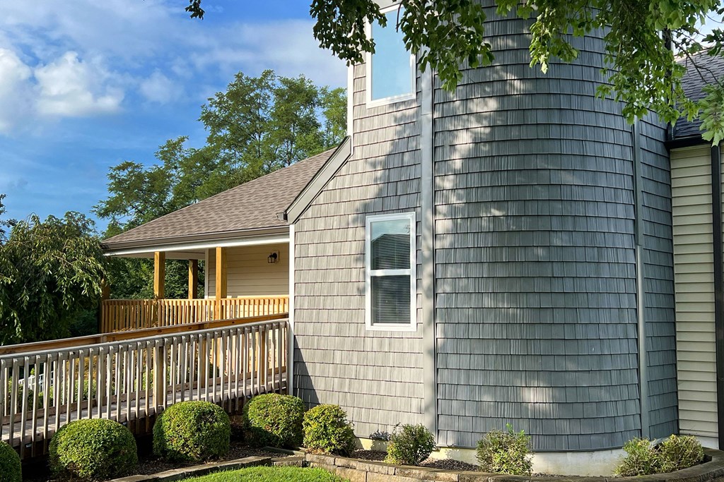 a gray house with a porch and a gray shingle roof at 450 on Keeneland Apartments, Richmond, 40475