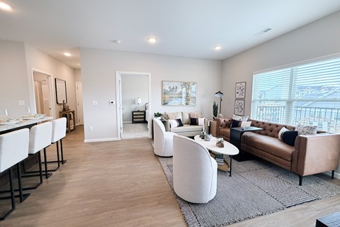 A modern living room with white furniture and a large window.
