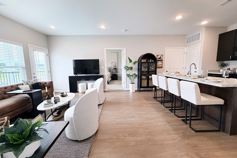 A modern kitchen with white chairs and a wooden floor.