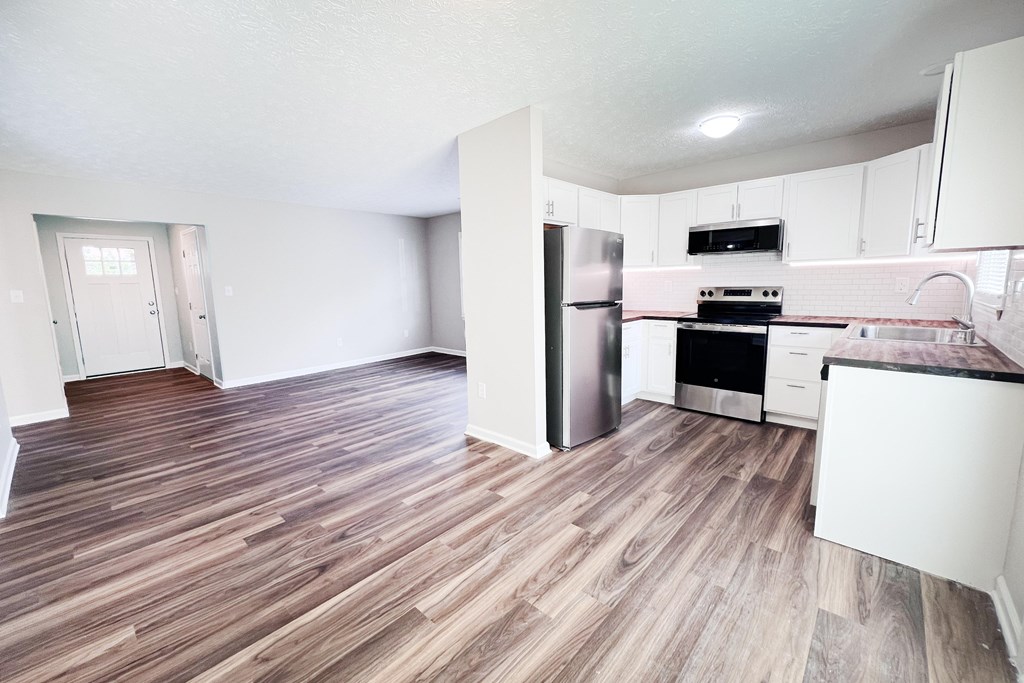 A kitchen with a refrigerator, oven, and stove top.