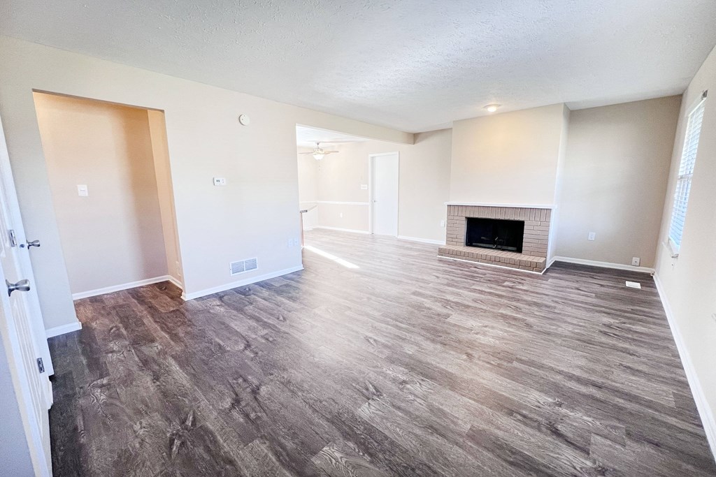 A room with a fireplace and wood flooring.