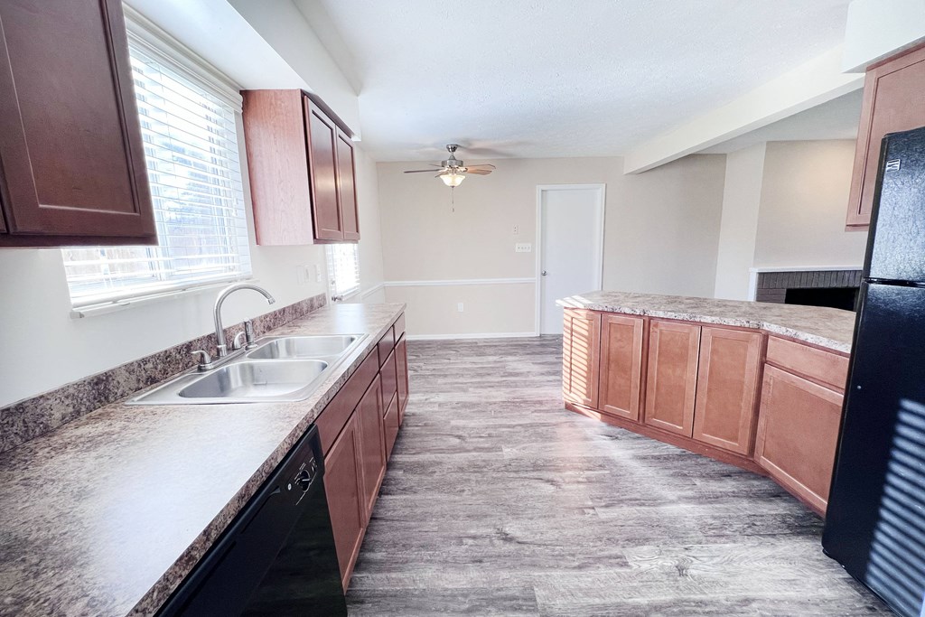 A kitchen with brown cabinets and a black fridge.