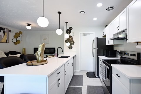 A modern kitchen with white cabinets and black appliances.