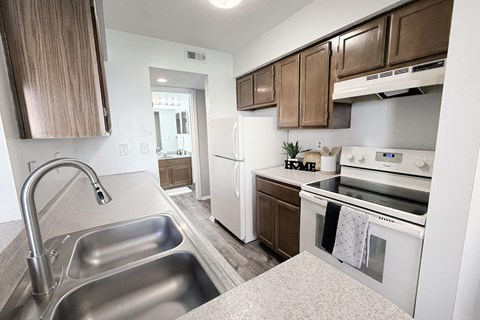 A kitchen with a stainless steel sink and white appliances.