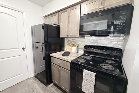A black stove and refrigerator in a kitchen.