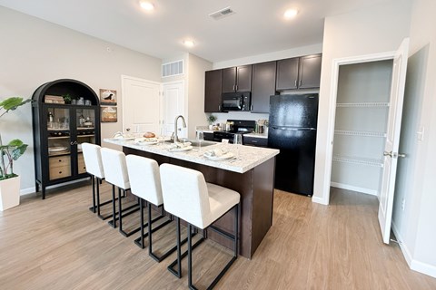 A kitchen with a bar area and white chairs.