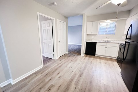 A kitchen with a black refrigerator and wooden floors.
