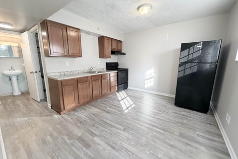 A kitchen with wooden cabinets and a black refrigerator.