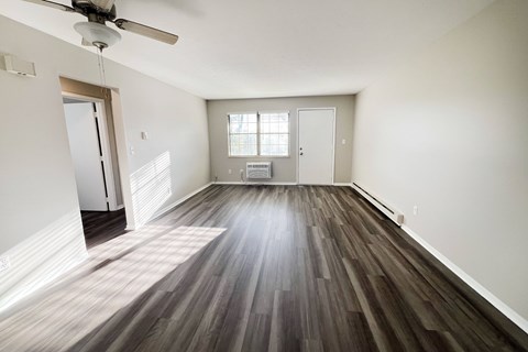 A room with a ceiling fan and wooden flooring.