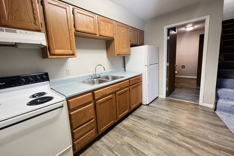 A kitchen with wooden cabinets and a white stove.