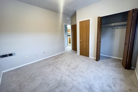 A spacious room with a carpeted floor and a door on the right side.