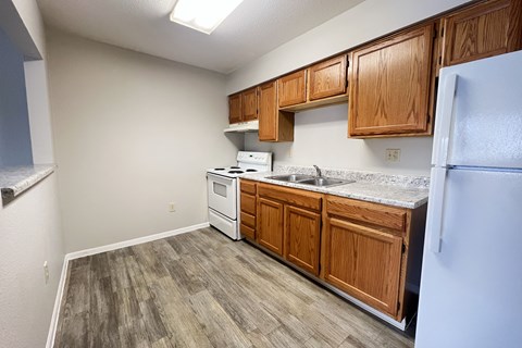 A kitchen with wooden cabinets and a white fridge.