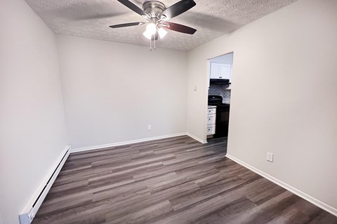 A room with a ceiling fan and wooden flooring.