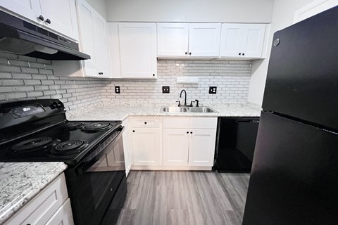 A kitchen with black appliances and white cabinets.