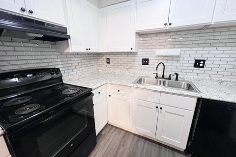A kitchen with a black stove top oven and white cabinets.