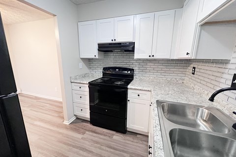 A kitchen with white cabinets and a black dishwasher.