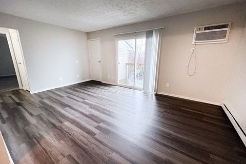 A room with wooden flooring and a window with blinds.