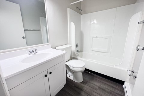A white bathroom with a toilet, sink, and bathtub.