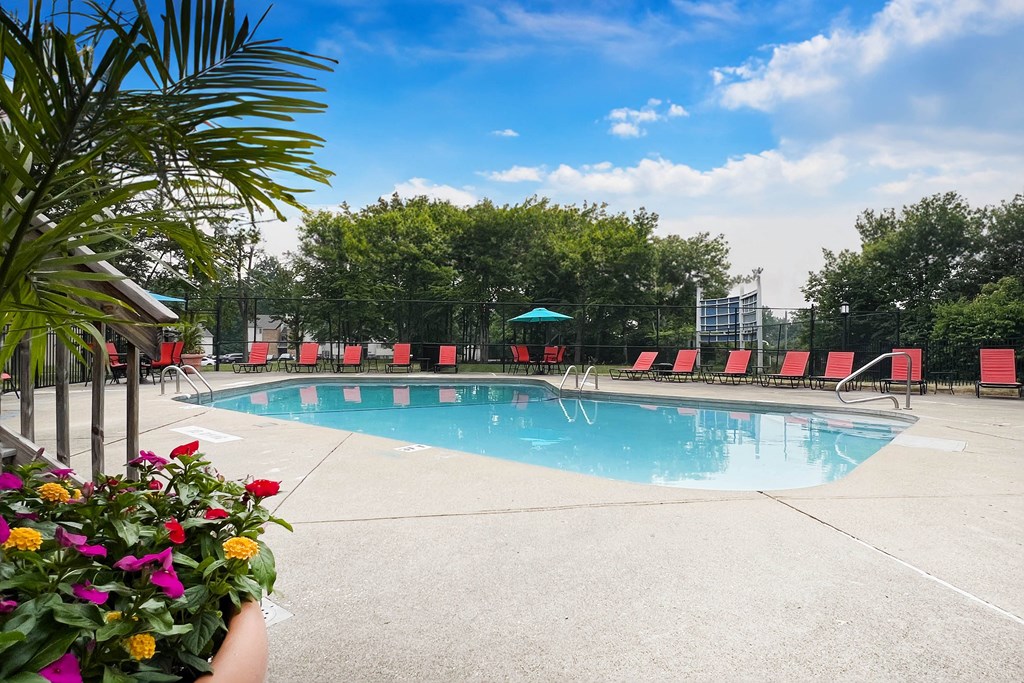 a swimming pool with red lounge chairs and trees in the background  at Hunter's Creek Apartments, Cincinnati