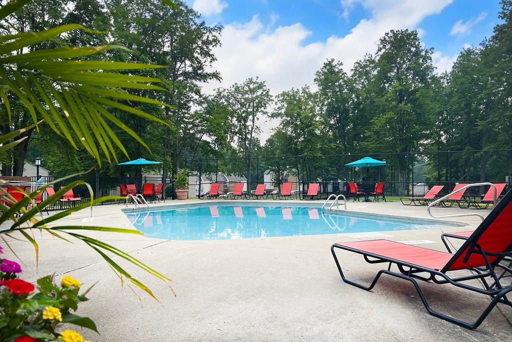 a swimming pool with red chaise lounge chairs and umbrellas  at Hunter's Creek Apartments, Cincinnati, Ohio