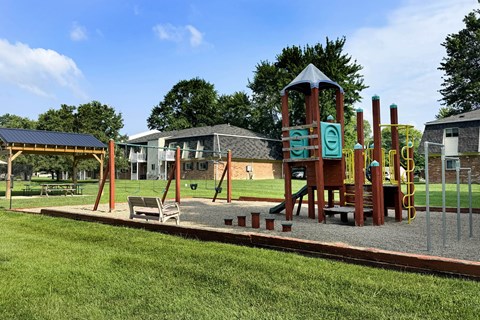 A playground with a wooden swing set and a green slide.