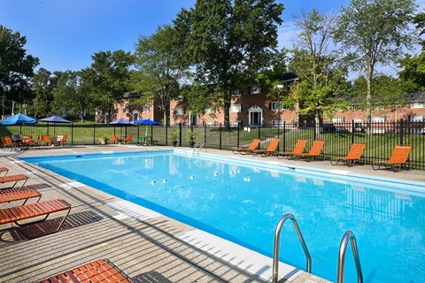 a swimming pool with orange chairs and a fence around it at Sharondale Woods Apartments, Cincinnati