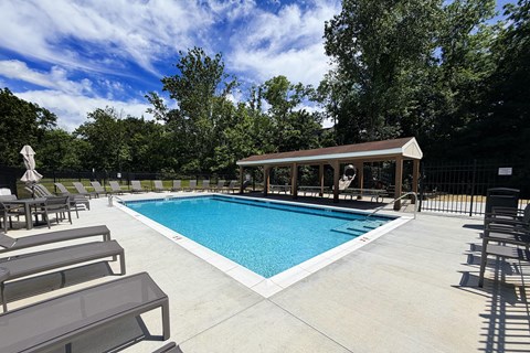 A pool with a sun lounger and a small building.
