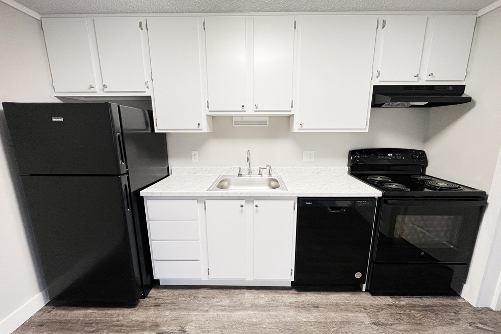 a kitchen with white cabinets and black appliances and a black refrigerator  at Wentworth Estates Apartments, Florence, Kentucky