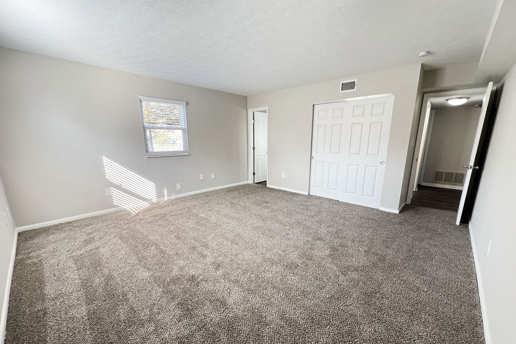 an empty living room with carpet and a white door
