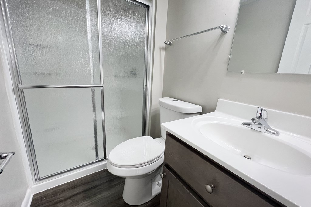 A white toilet sits next to a sink in a bathroom at Revere Village Apartments, Ohio, 45458