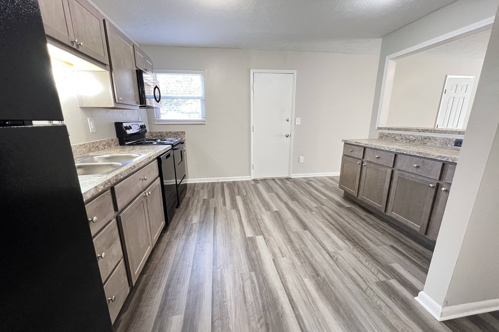 A kitchen with a black refrigerator and wooden floors at Revere Village Apartments, Centerville, Ohio