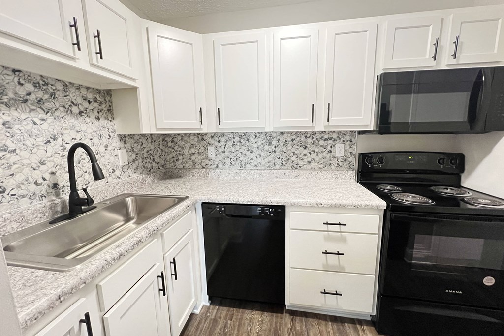 a kitchen with white cabinets and black appliances and a sink at 450 on Keeneland Apartments, Richmond, KY