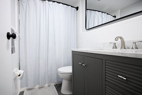 A white toilet sits under a shower curtain in a bathroom.