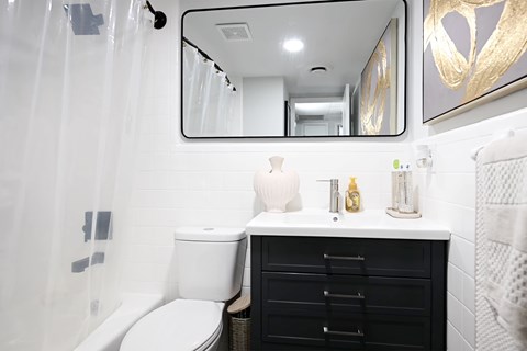 A white toilet sits next to a black cabinet in a bathroom.