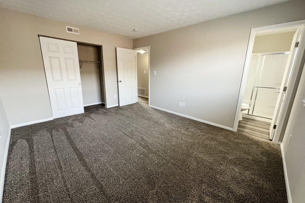 an empty living room with carpeting and a door to a closet at Revere Village Apartments, Ohio, 45458