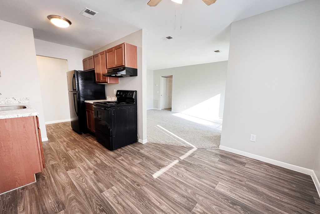 A kitchen with a black fridge and a wooden floor.