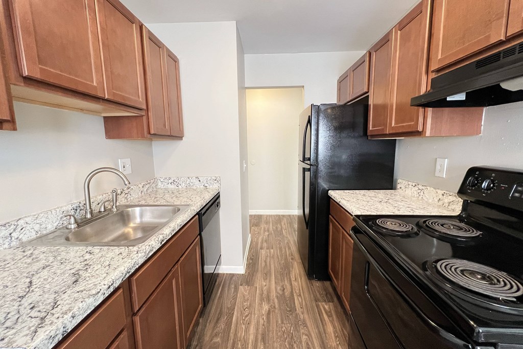 A kitchen with a black fridge and stove top oven.