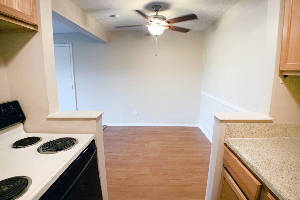 A kitchen with a stove top oven and a ceiling fan.