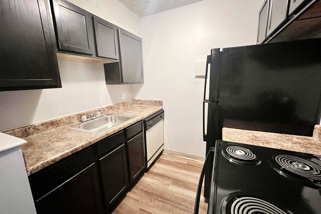 A kitchen with black cabinets and a black stove.