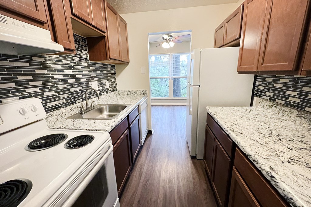 A kitchen with white appliances and brown cabinets.