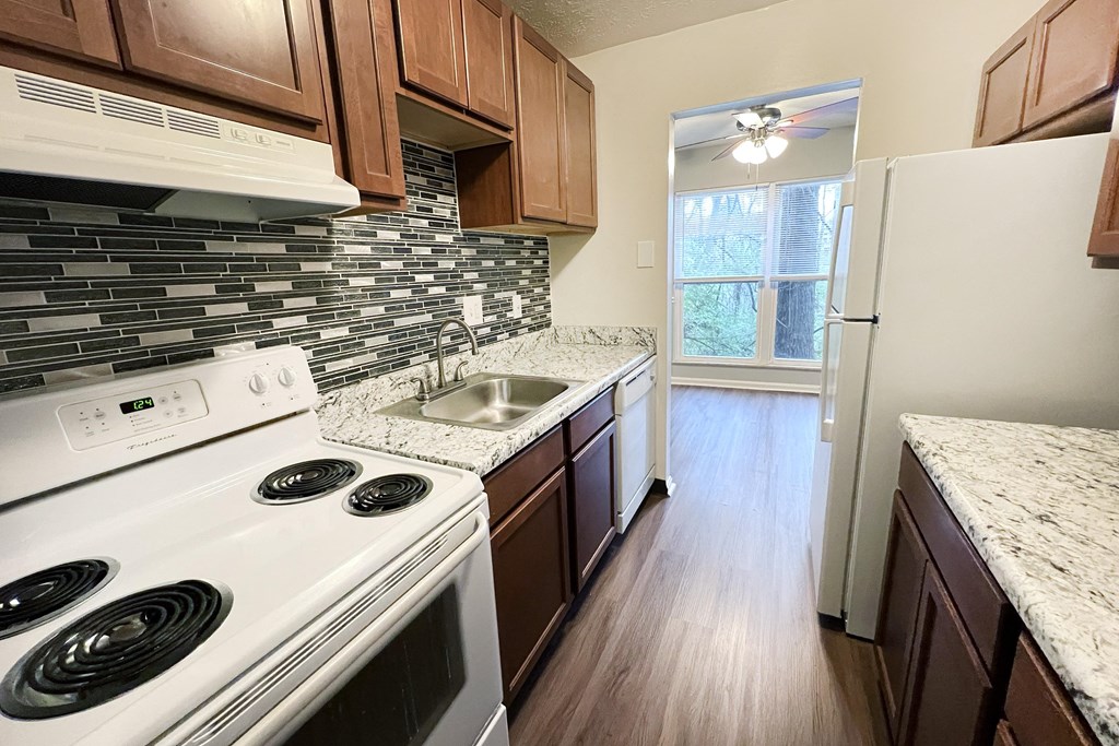 A kitchen with a white stove top oven and a white refrigerator.