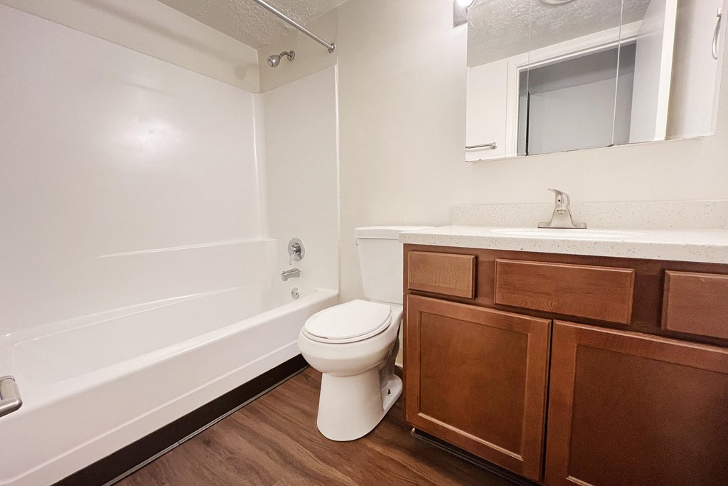 A white toilet sits in a bathroom next to a white bathtub.