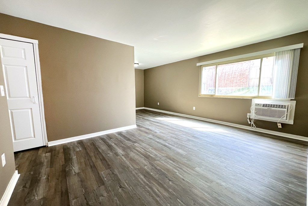 A room with brown walls and wooden flooring with a white door and window.