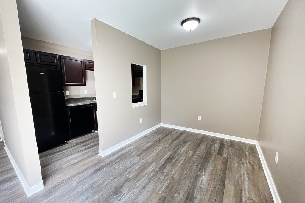 A kitchen with a black fridge and wooden flooring.