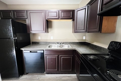A kitchen with dark brown cabinets and black appliances.