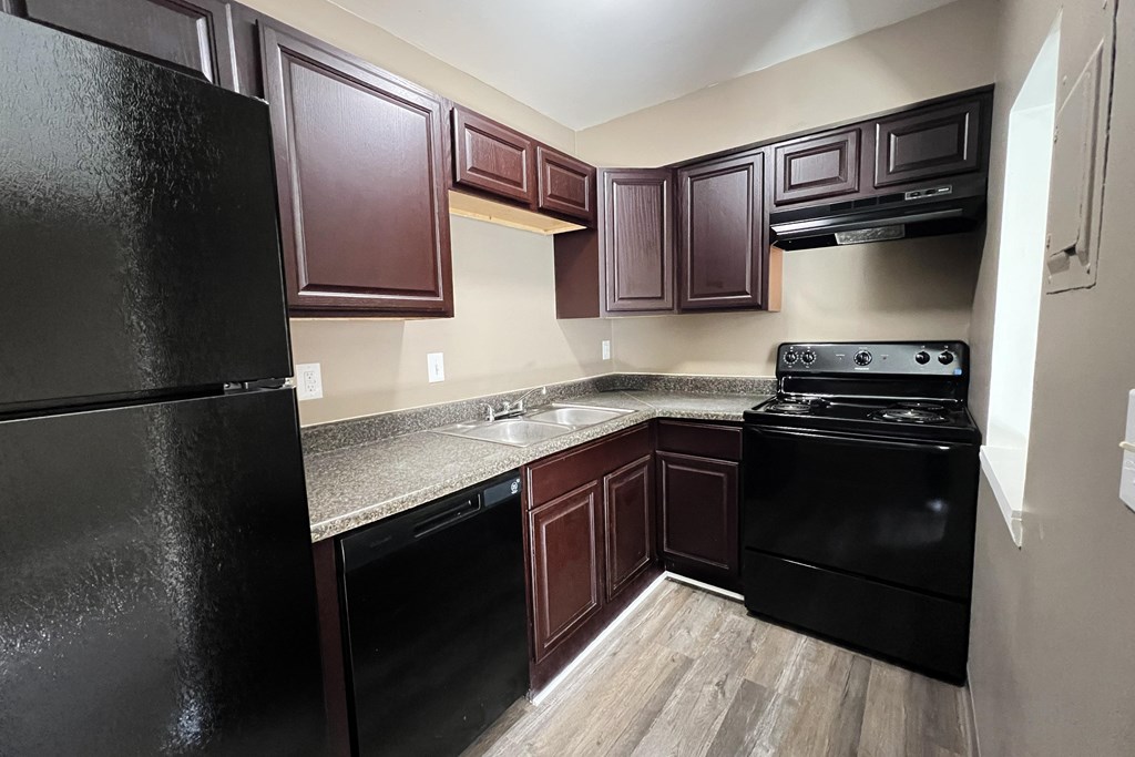 A kitchen with dark wood cabinets and black appliances.