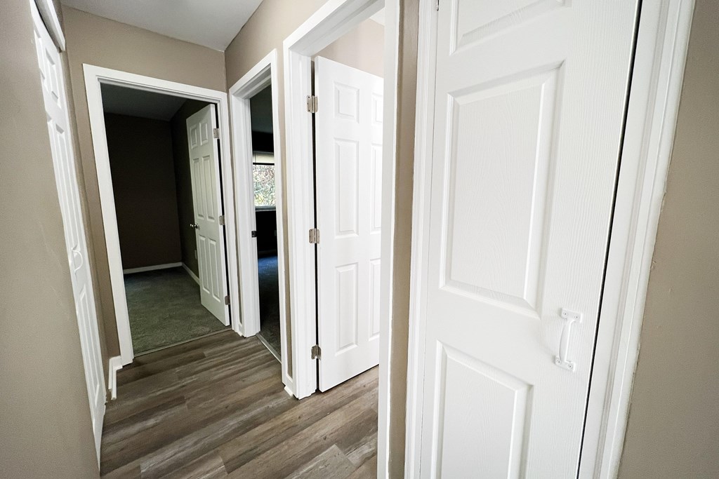 A hallway with white doors and a wooden floor.