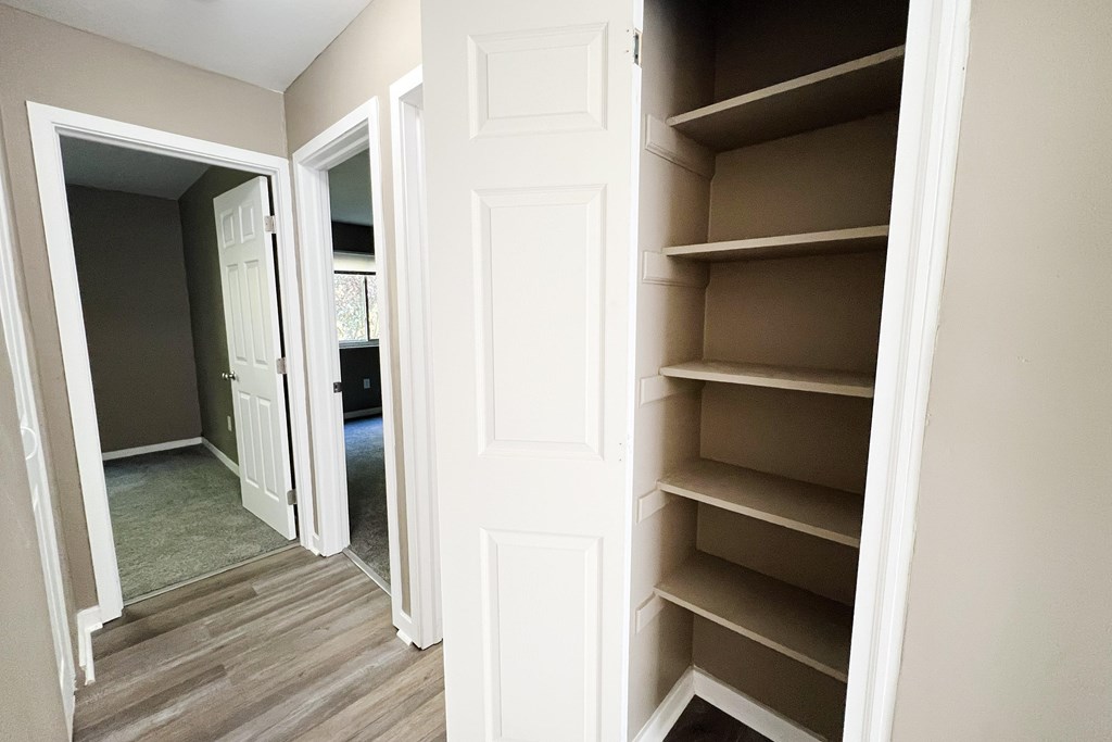 A white door is open to a room with a brown floor.