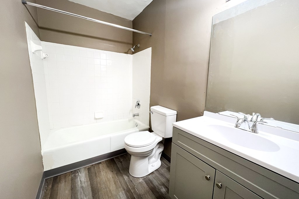 A white toilet sits next to a bathtub in a bathroom.